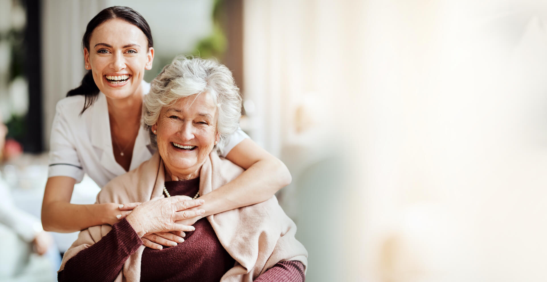 Caregiver and senior resident smiling together