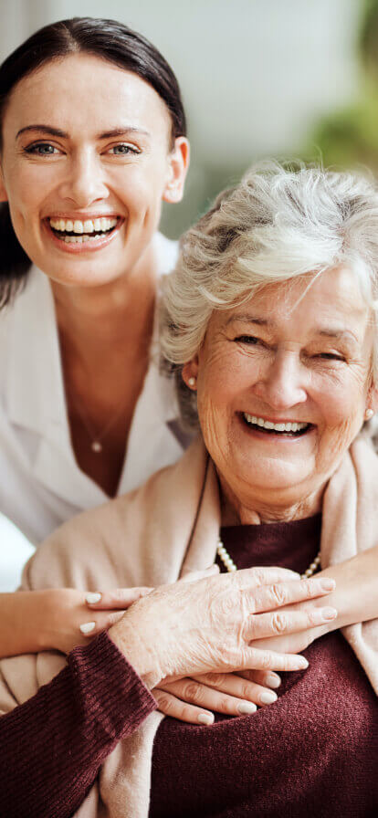 Caregiver and senior woman smiling together.