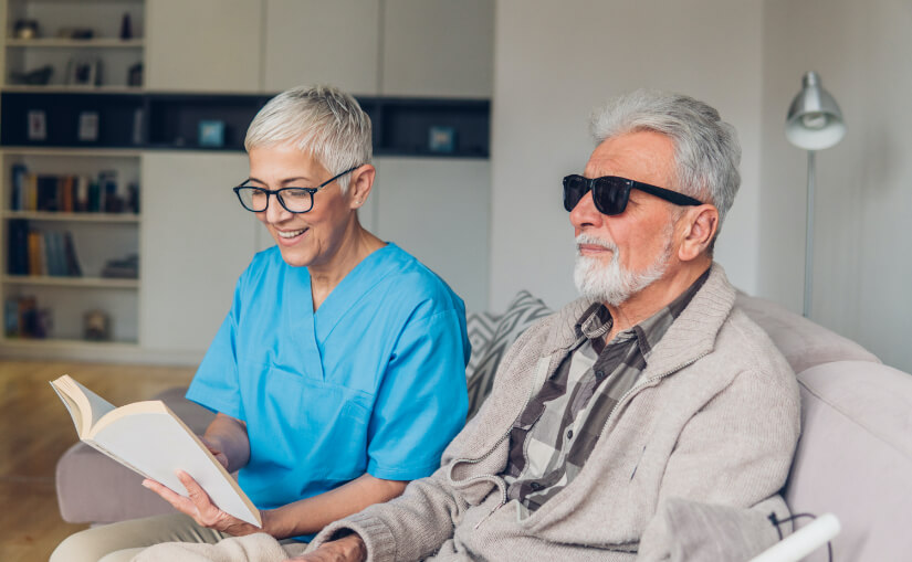 Caregiver reading to a senior resident at home.