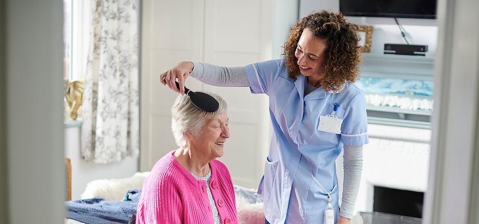 Caregiver brushing a resident's hair in a cozy room.