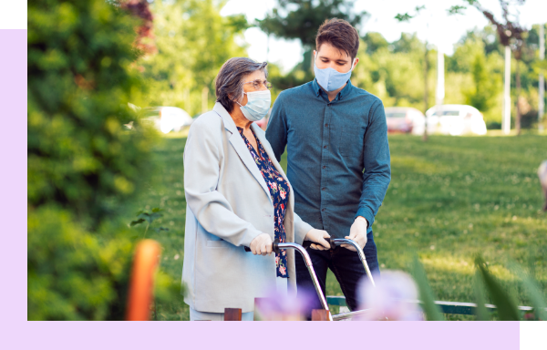 Staff assisting a resident outdoors in a garden.