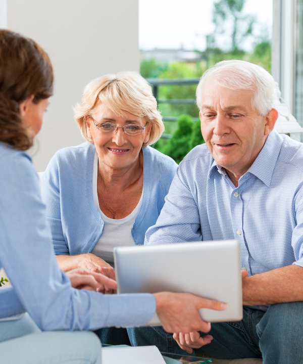 Elderly couple engaging with a caregiver in a common area.