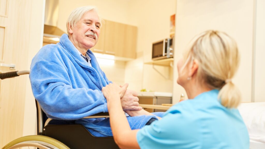Caregiver interacting with a resident in a wheelchair.