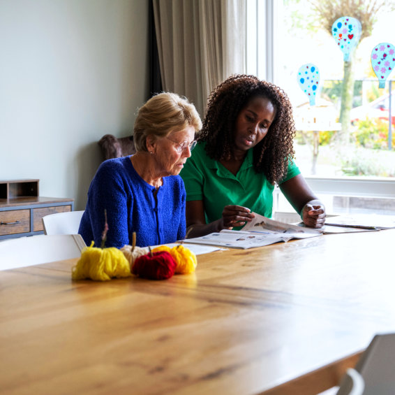 Two women engaged in a creative activity at a table.