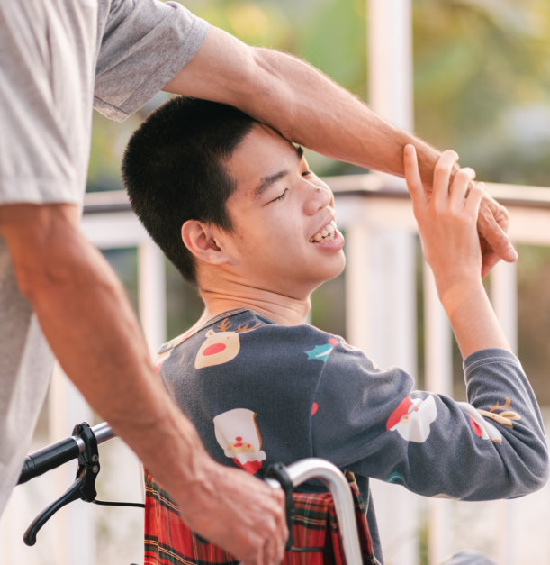 A young resident in a wheelchair smiling outdoors.