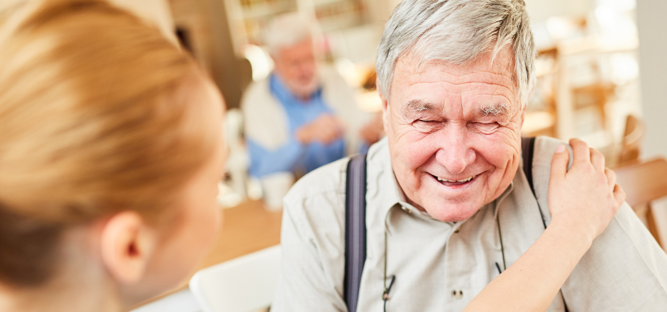 Smiling elderly man engaged with staff member