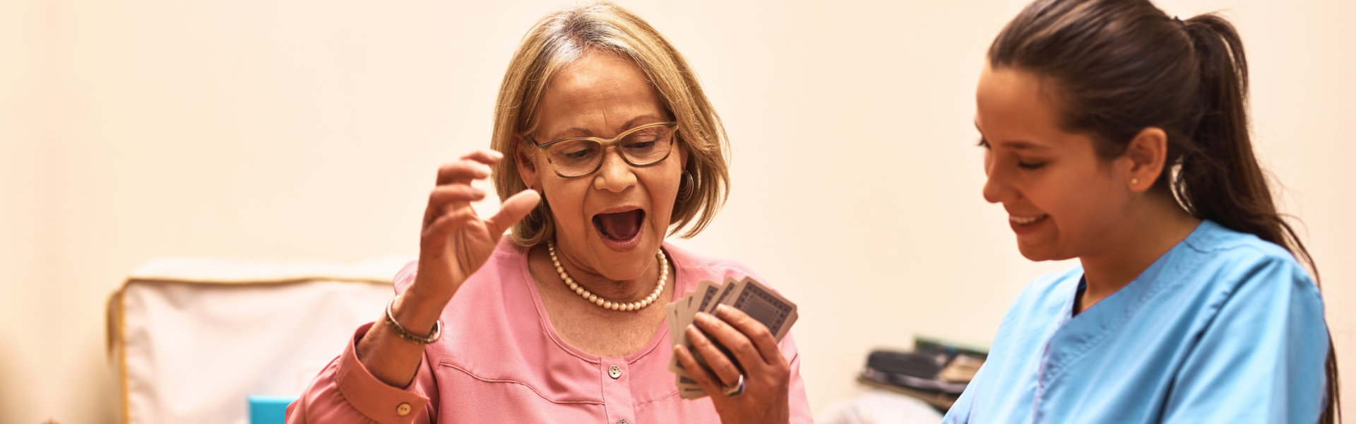 Senior woman enjoying card games with staff member