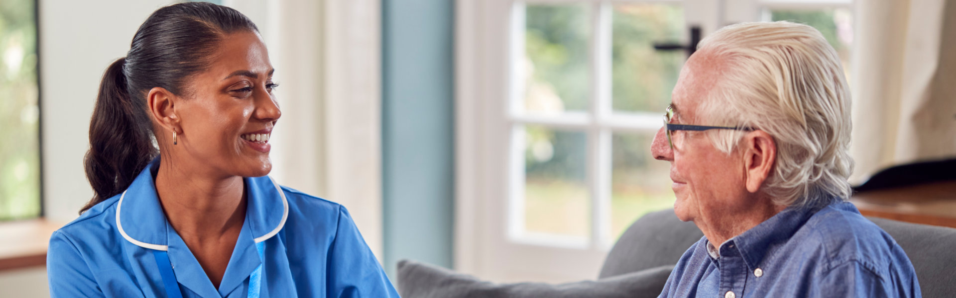 A caregiver smiling and talking with a senior resident.