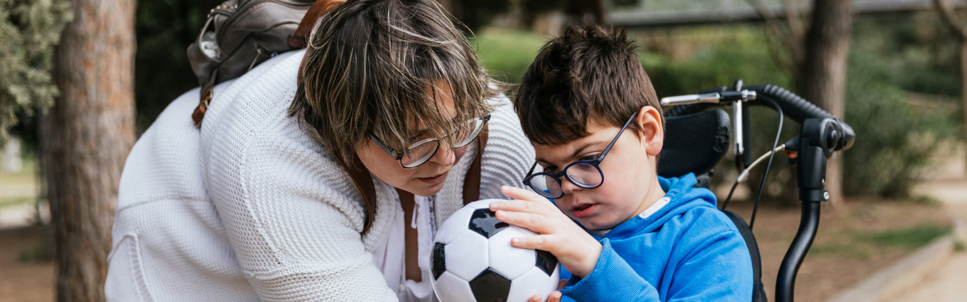Caregiver assisting child with a soccer ball