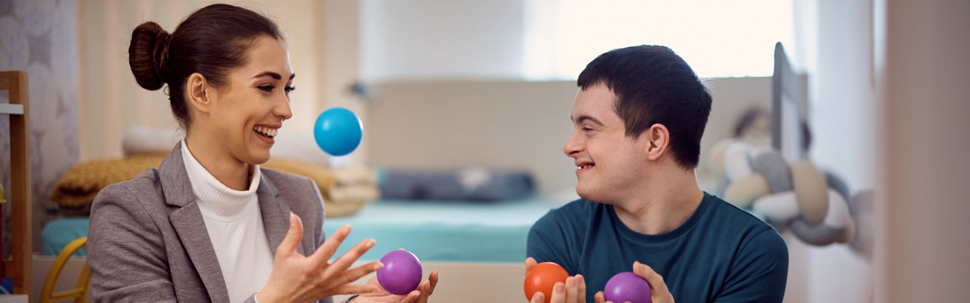 Staff member and resident enjoy playing with colorful balls.