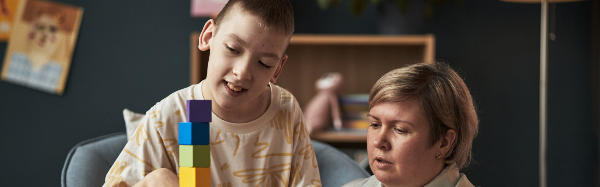 Child and caregiver playing with colorful building blocks.