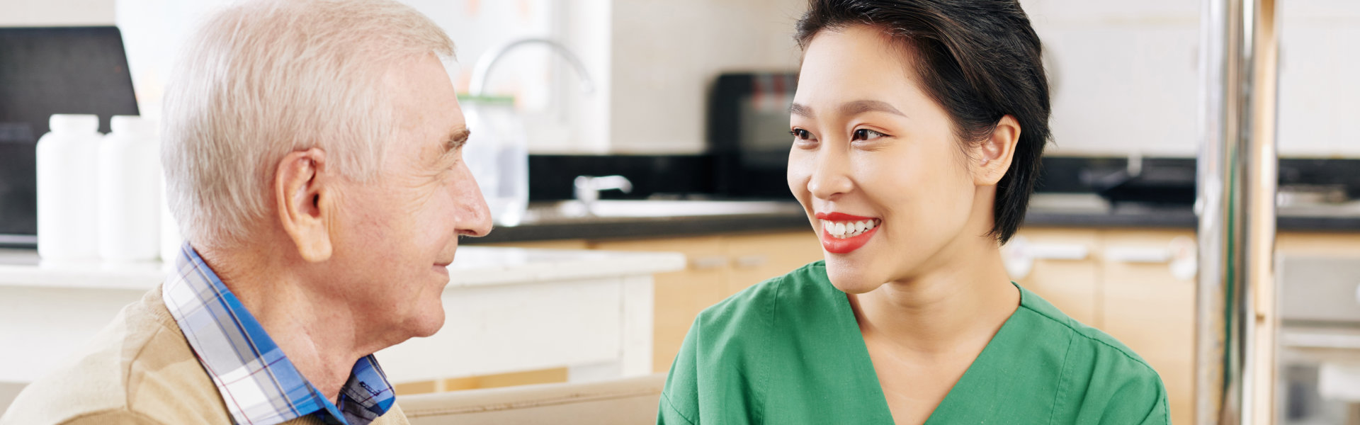 Smiling nurse interacts with senior resident indoors.