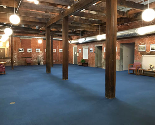 Spacious common area with exposed beams and blue carpet.