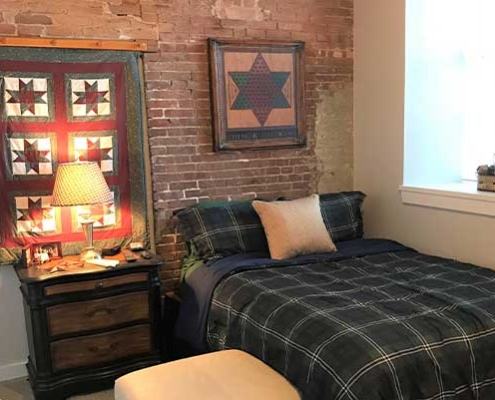 Cozy bedroom with quilt and brick wall