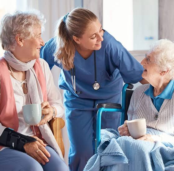Caregiver interacting with two elderly residents indoors.