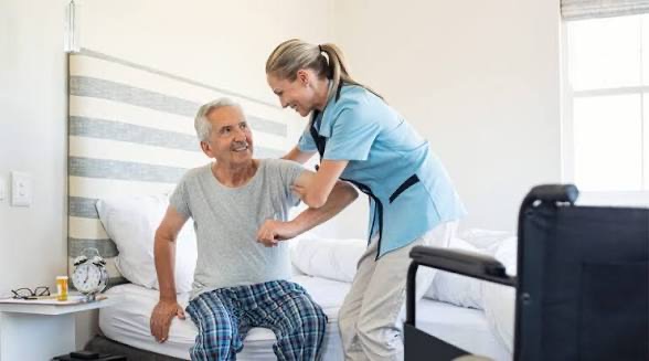 Caregiver assisting an elderly man in his room.