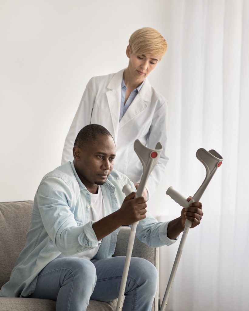 A resident using crutches with a staff member's assistance.