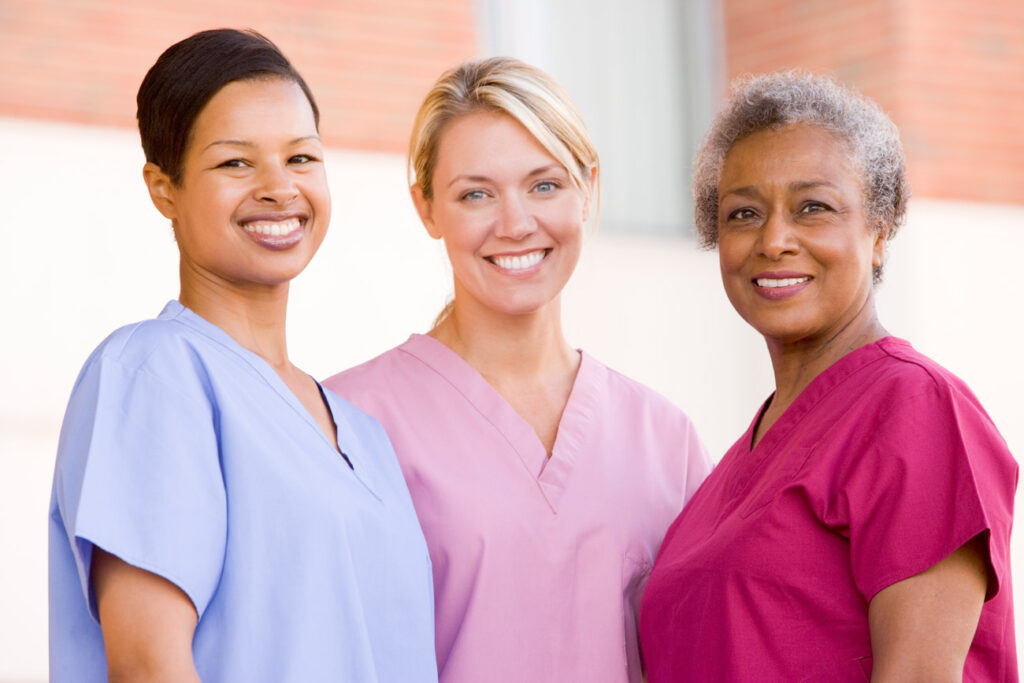 Three smiling healthcare staff members outdoors
