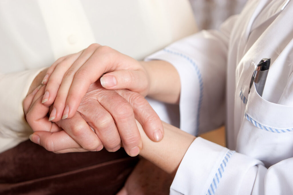 Caregiver holding a senior's hand gently