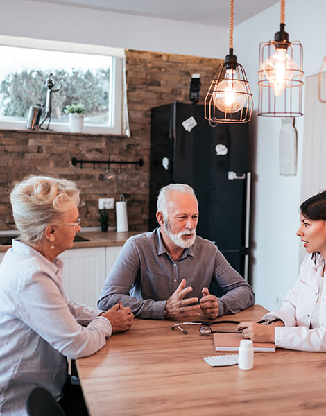 Seniors discussing with a healthcare professional in a kitchen