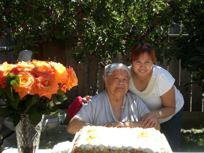Resident celebrating with a caregiver and cake outdoors.