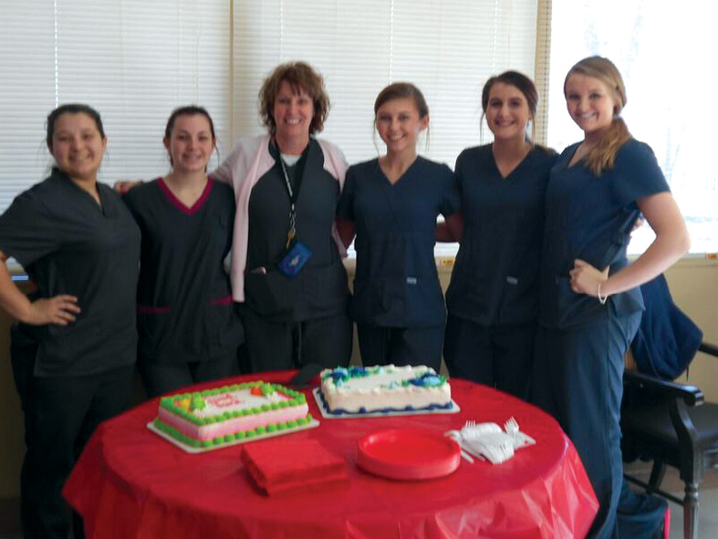 Staff members celebrating with cakes in a common area.