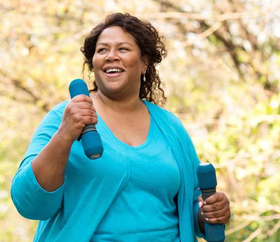 Woman exercising with dumbbells in a garden