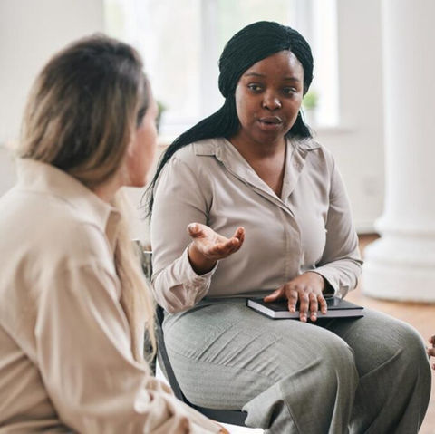 Two staff members engaged in conversation indoors.