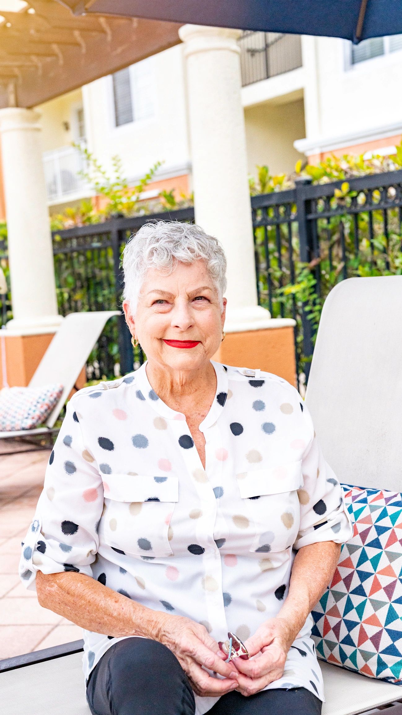 Senior woman smiling outdoors near pool area.