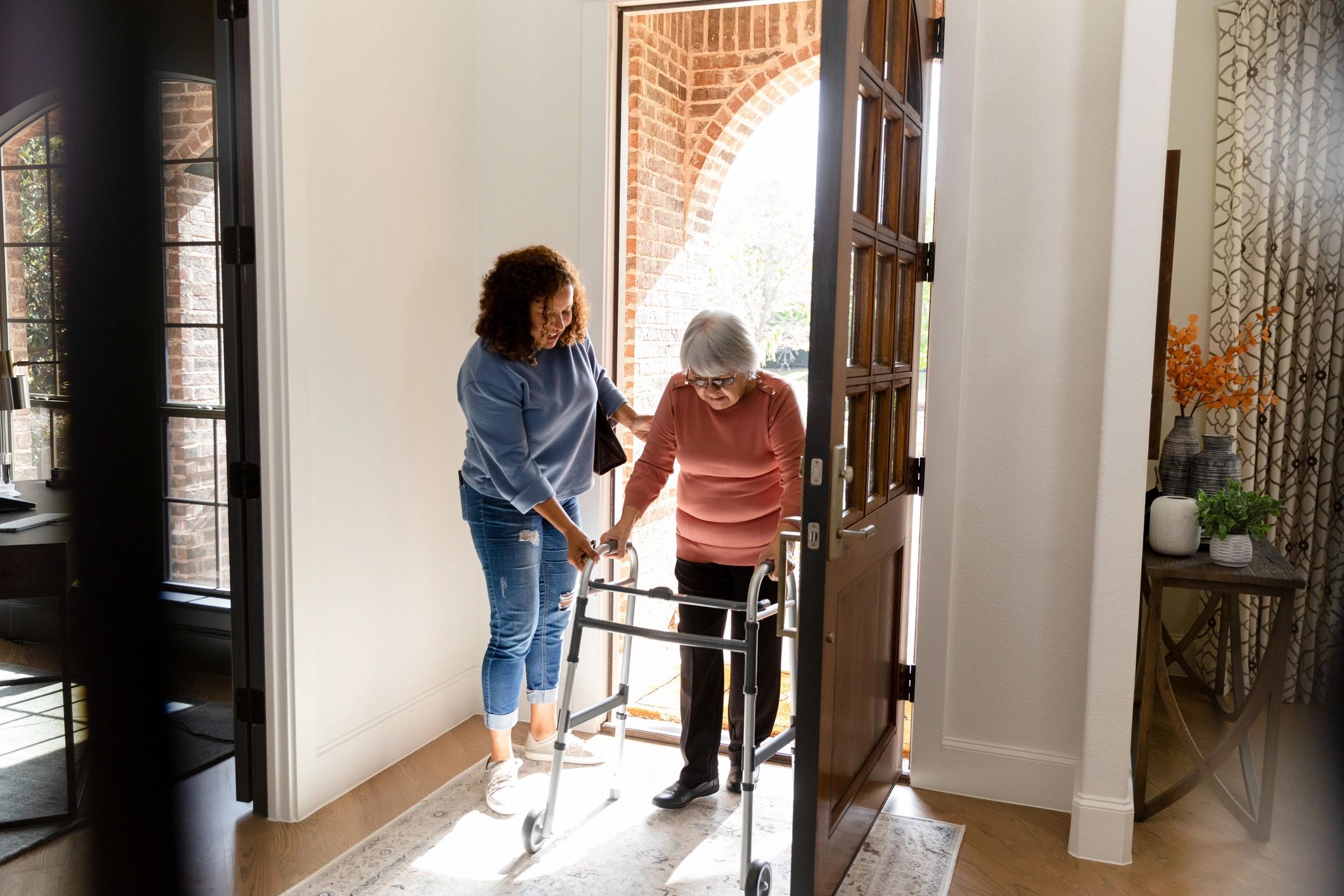 Caregiver assisting senior woman at doorway