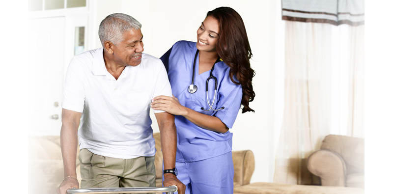 Nurse assisting an elderly man indoors