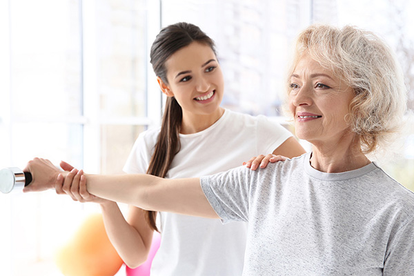 Senior woman exercising with assistance from a caregiver.