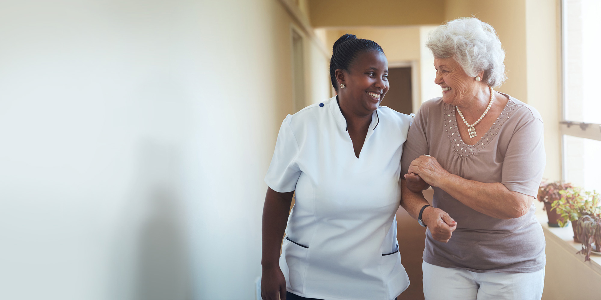 Nurse assisting an elderly woman in a hallway