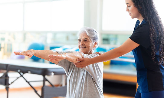 Staff assisting an elderly resident with therapy exercises.