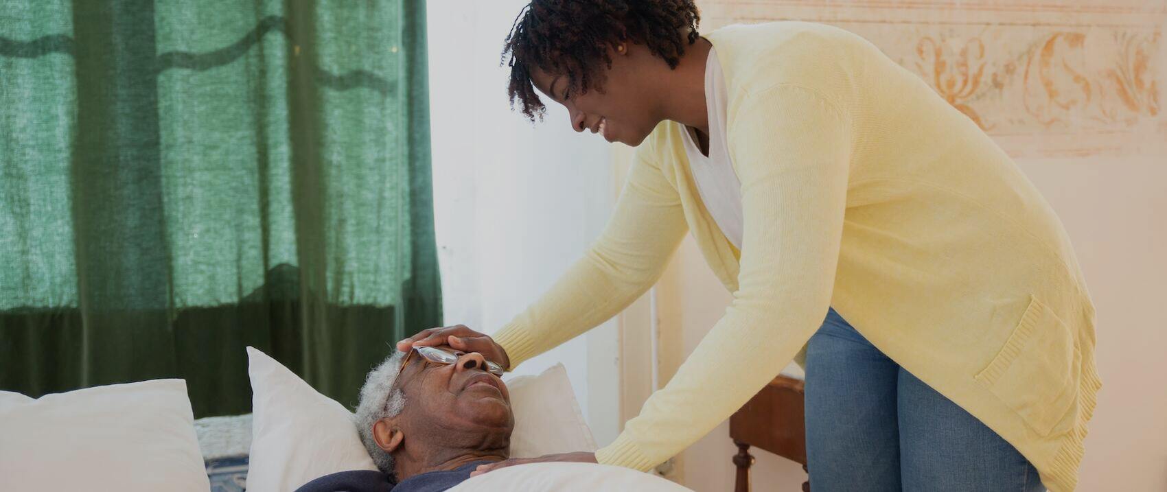 Caregiver assisting an elderly resident in bed.