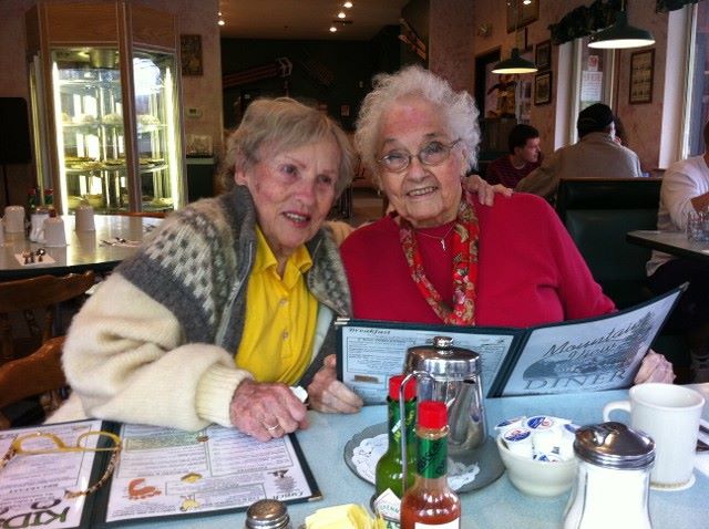Two elderly women enjoying a meal at a diner