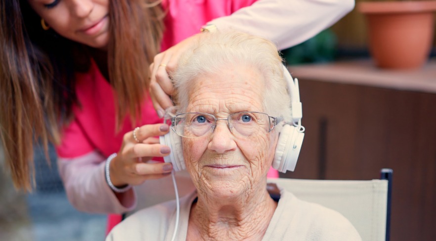 Elderly woman enjoying music with a caregiver.