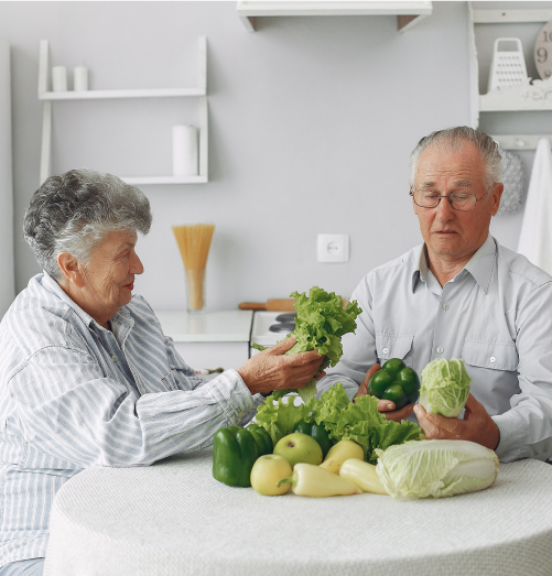 Seniors engaging with fresh vegetables in a kitchen.