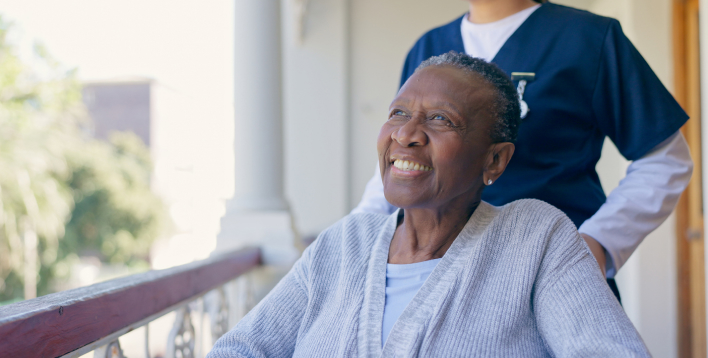 Smiling elderly woman in wheelchair with caregiver.