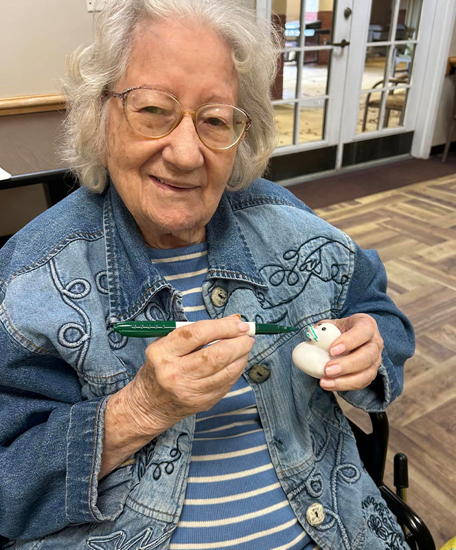 Senior resident painting a decorative rock