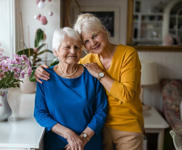 Two women smiling in a cozy interior setting.