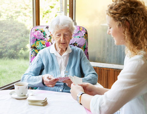 Senior resident playing cards with staff member