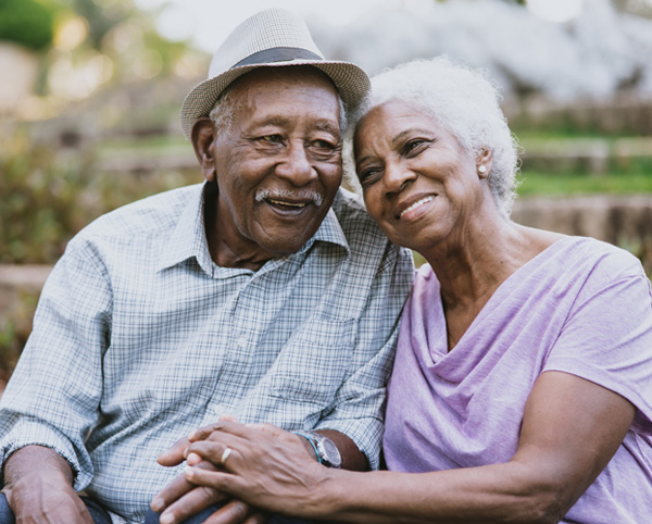 Two elderly individuals smiling together outdoors