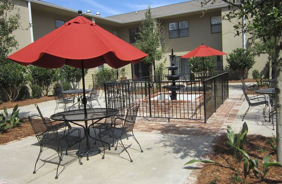 Outdoor seating area with red umbrellas and a fountain.