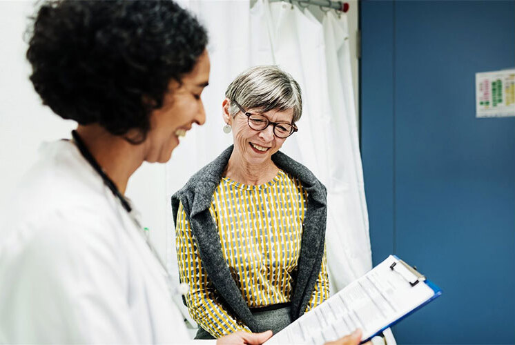 A senior woman and a healthcare worker smiling together.
