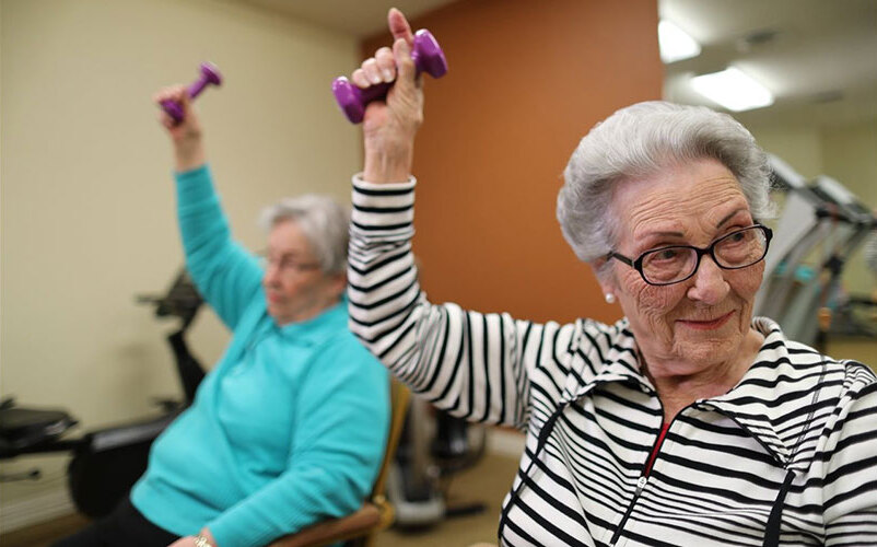 Seniors engaged in exercise with weights.