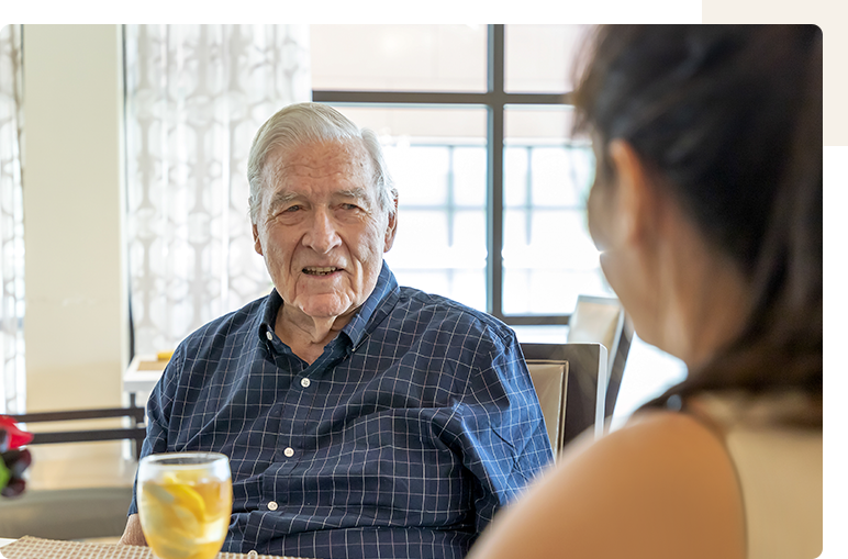 Senior man engaged in conversation with staff member.
