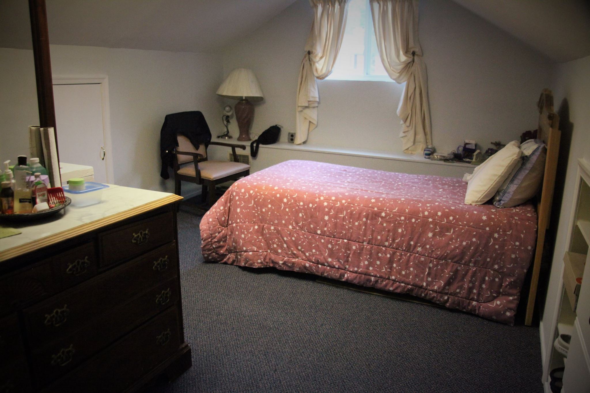 A cozy resident room with a bed and dresser