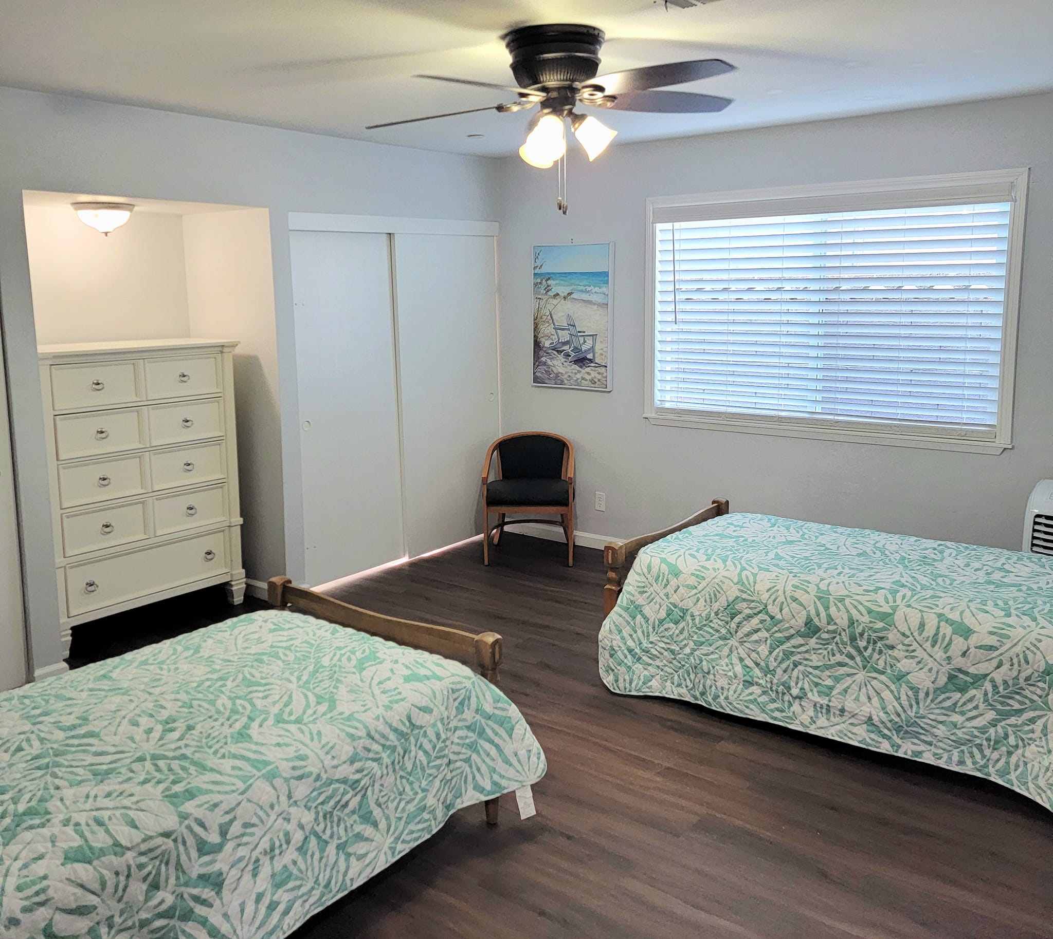 A brightly lit shared room with twin beds and dresser