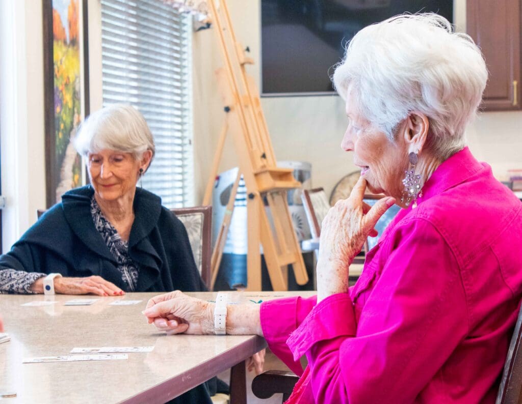 Two elderly women enjoying a card game in a common area